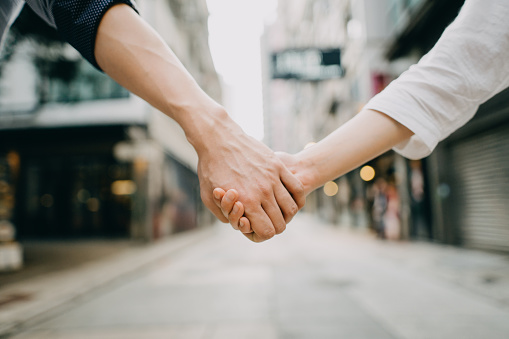Close up of couple holding hands against city street scene