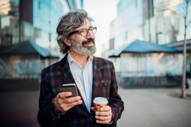 istock Man holding cup of coffee and using phone 1144963065