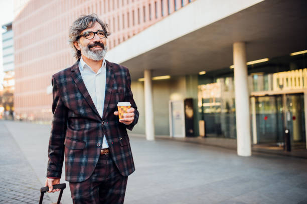 istock Man pulling luggage and holding cup of coffee 1144963121