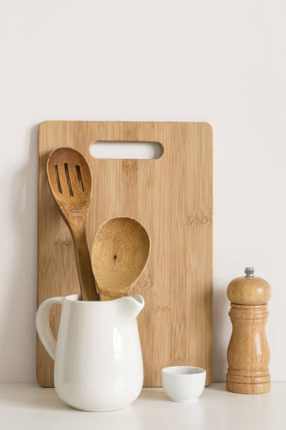 istock Cutting board, spoons and spice mill on table wall background 1144963585
