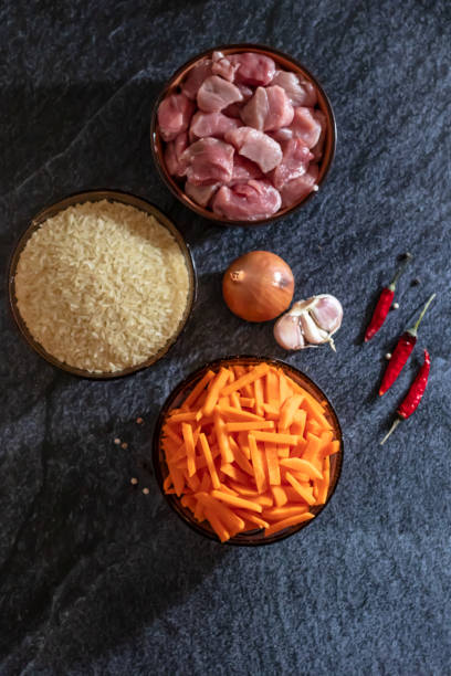 istock Ingredients for making pilaf, rice, meat, onions and carrots on a dark background 1144964962