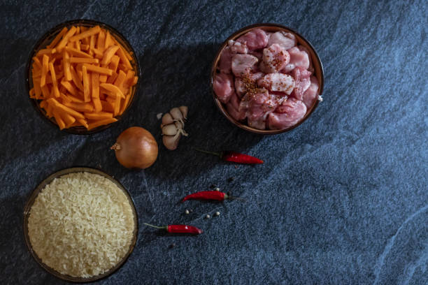 istock Ingredients for making pilaf, rice, meat, onions and carrots on a dark background 1144965686