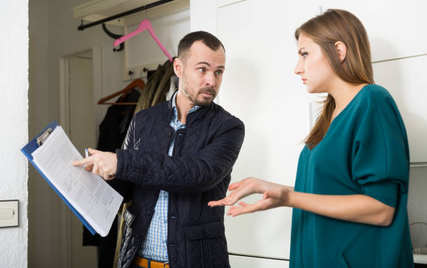 Frustrated woman talking to debt collector Portrait of young frustrated woman talking to debt collector visiting her at home and demanding to pay debts tenant stock pictures, royalty-free photos & images