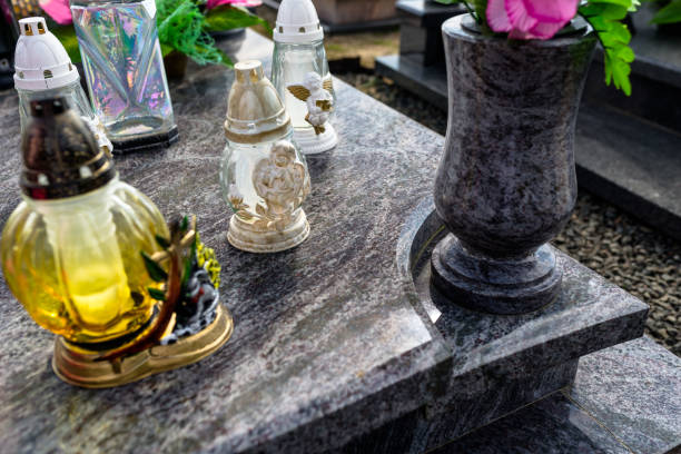 istock Candlesticks and a vase with flowers lying on a marble, dark tombstone. 1144977806