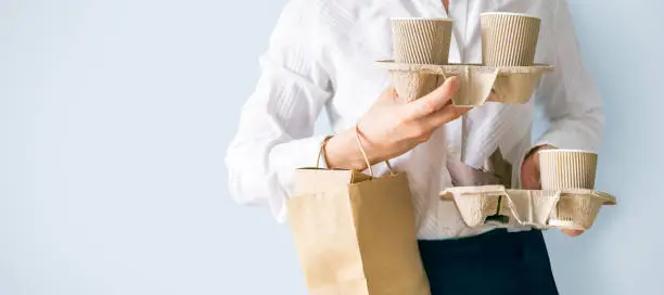 Photo of Female holding coffee containers, paper bag withfood containers. Food and coffee delivery
