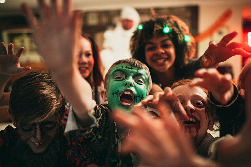 Group of young friends dressed in costumes reaching out towards the camera like zombies.