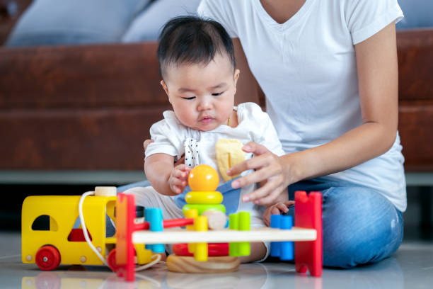 Mother play with her baby by wooded toy in living room Mother play with her baby by wooded toy in living room, this image can use for family, insurance and mon concept asian nanny stock pictures, royalty-free photos & images