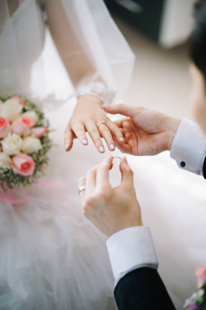 istock Bridegroom putting on the wedding ring for the bride 1144984565