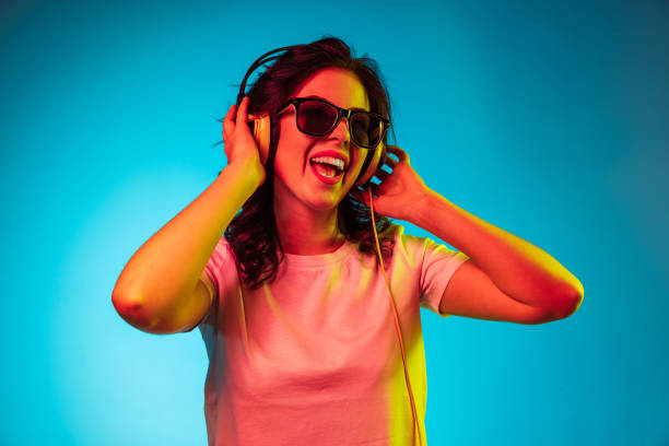 feliz joven mujer de pie y sonriendo contra el fondo azul - tourist resort audio fotografías e imágenes de stock