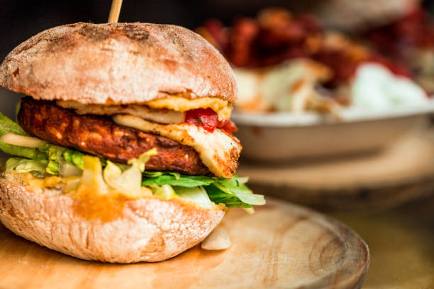 frisch gegrillte vegetarische halloumi cheeseburger auf holztheke auf lebensmittelmarkt - fleischersatz stock-fotos und bilder