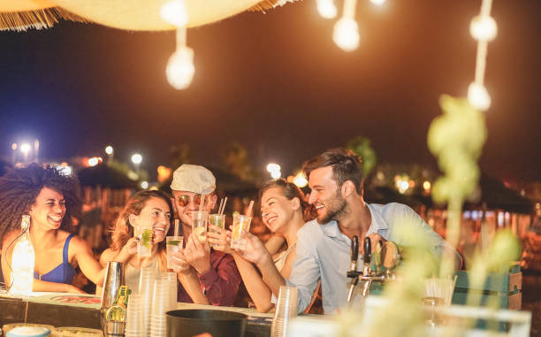 幸せな友人は、ビーチパーティー屋外でのカクテルを応援し、お酒を飲んで、週末夏の夜に楽しみを持つ若いミレニアル世代-若者のライフスタイルとナイトライフコンセプト-右の人に主な� - friendship party young adult beach ストックフォトと画像