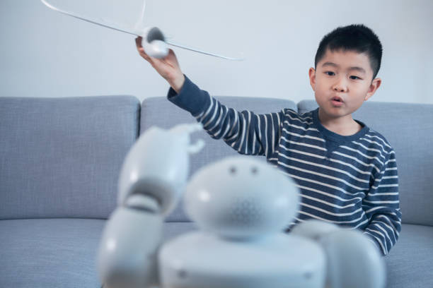 istock Smart boy showing model airplane with robot indoors 1144994630