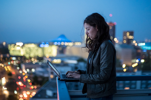 young woman, typing, laptop, illuminated, cityscape, Berlin, twilight