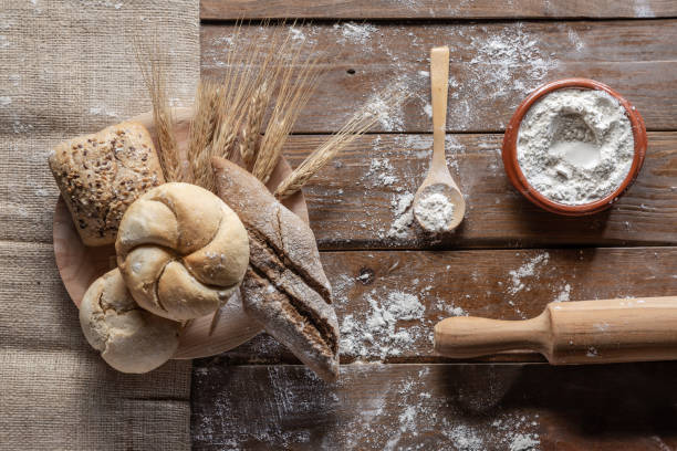 istock bread with wheat ears and flour on wood board, top view 1144999536