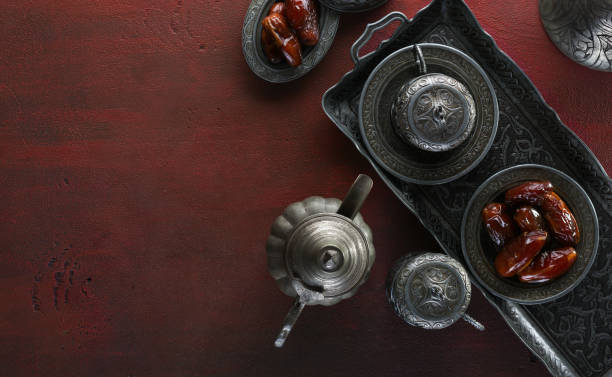 Top view on silver plate with date fruits and coffee cups on the dark red wooden background. Ramadan background. Ramadan kareem. Top view on silver plate with date fruits and coffee cups on the dark red wooden background. Ramadan background. Ramadan kareem. iftar photos stock pictures, royalty-free photos & images