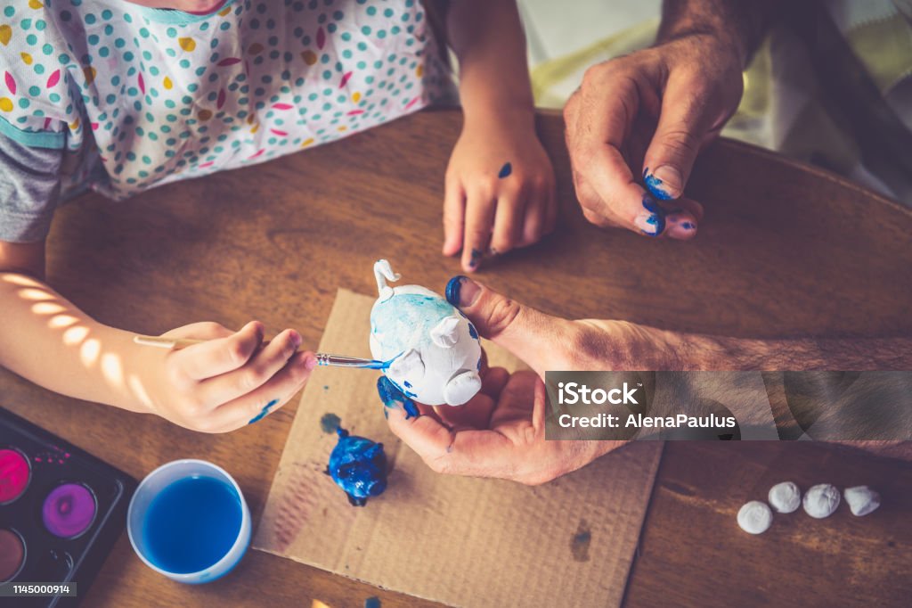 Father and son painting Clay Handmade Little Piggy Bank Father and son painting together. Child Stock Photo
