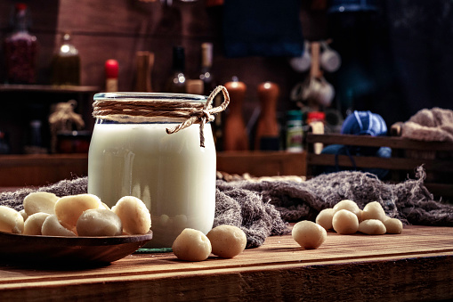 Non-dairy macadamia milk in glass and jar with nuts in old fashioned rustic kitchen