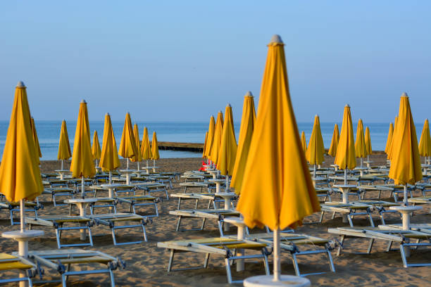 schließlich beginnt der sommer mit den noch am strand geschlossenen sonnenschirmen - italy adriatic sea summer europe stock-fotos und bilder