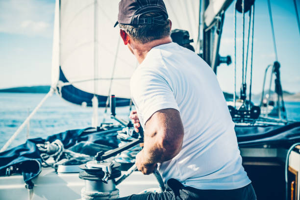 A sailing crew member on sailboat during a regatta adjusting jib sail on sunny autumn morning,