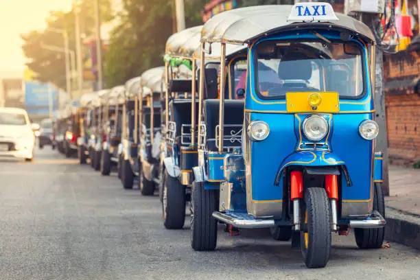 A row of tuk-tuks parked along a city street in central Chiang Mai, Thailand.