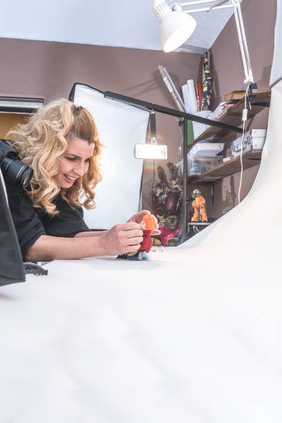 istock Woman Artist in Home Studio Creating Stop Motion Animated Video, Using Digital Camera to Capture Puppets Frame by Frame to Produce the Appearance of Movement 1145005735
