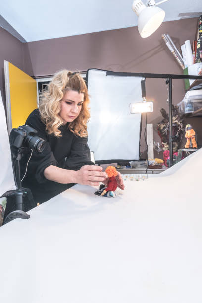 istock Woman Artist in Home Studio Creating Stop Motion Animated Video, Using Digital Camera to Capture Puppets Frame by Frame to Produce the Appearance of Movement 1145005750