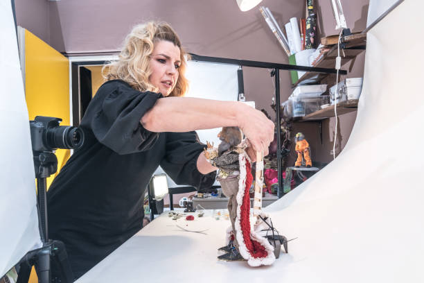 istock Woman Artist in Home Studio Creating Stop Motion Animated Video, Using Digital Camera to Capture Puppets Frame by Frame to Produce the Appearance of Movement 1145005759