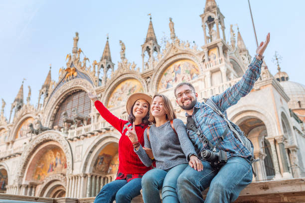 grupo de amigos felices viajeros que se divierten en la plaza de san marcos en venecia. vacaciones y vacaciones en italia y europa concepto - cathedral group fotografías e imágenes de stock