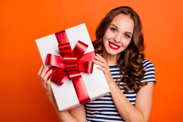 Close up photo beautiful she her lady arms big large giftbox best guest family meeting red lips pomade excited funky wear casual striped white blue t-shirt clothes isolated orange bright background.