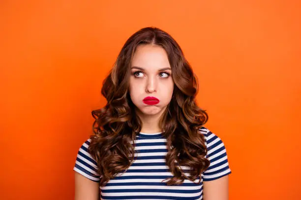Close up photo beautiful she her lady red lipstick hold breath full mouth air ignore not listen speak talk tell look up wear casual striped white blue t-shirt clothes isolated orange bright background.
