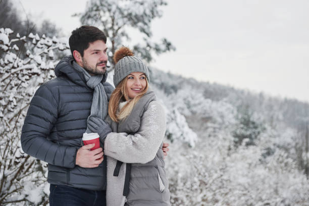 belle persone in piedi vicino alla foresta innevata. bella coppia hanno un fine settimana in campagna in inverno - snow heat adult blond hair foto e immagini stock