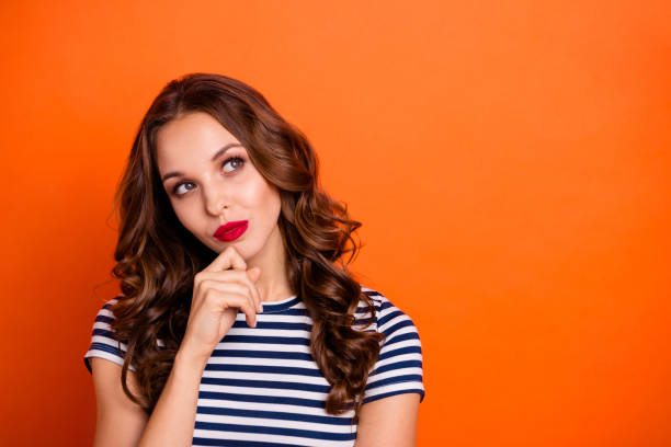 istock Close up photo beautiful she her lady tempting red lipstick eyes look empty space imaginary flight contemplation wear casual striped white blue t-shirt clothes isolated orange bright background 1145012024