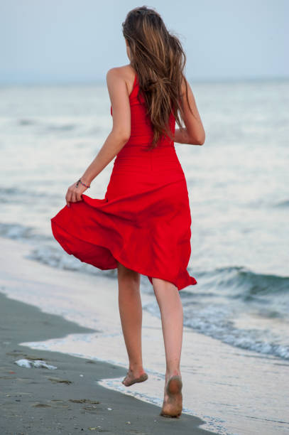 istock Young woman in red is running on the beach 1145014724
