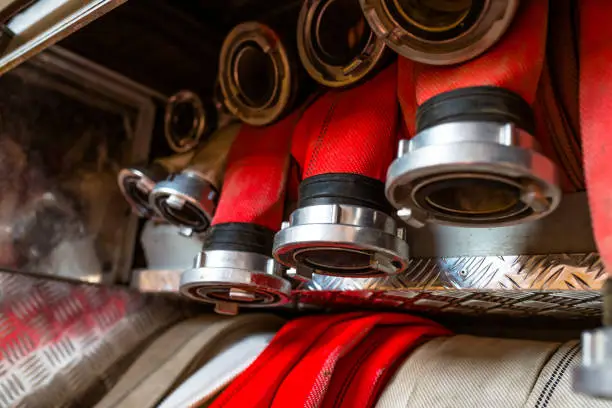 Rolled fire hoses, arranged in rows, in the glove compartment of the fire truck.