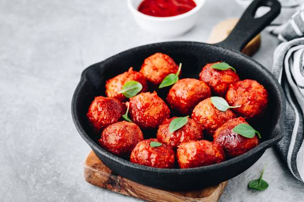 Homemade beef or chicken meatballs in tomato sauce in a frying pan Homemade beef or chicken meatballs in tomato sauce in a frying pan on gray stone background. chicken balls stock pictures, royalty-free photos & images