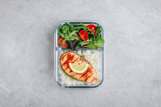 istock Meal prep containers with salmon and rice, green mix salad with tomatoes. 1145018043