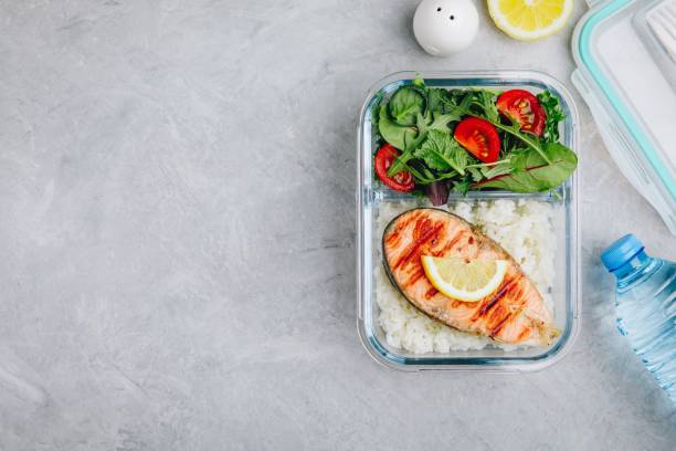 istock Meal prep containers with salmon and rice, green mix salad with tomatoes. 1145018063