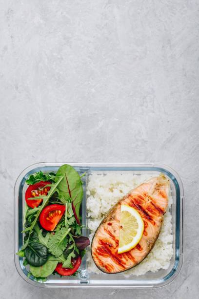 istock Meal prep containers with salmon and rice, green mix salad with tomatoes. 1145018076