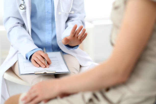 istock Doctor and patient talking. Physician at work in hospital while writing up medication history records form on clipboard near sitting woman. Healthcare and medicine concepts. 1145018283