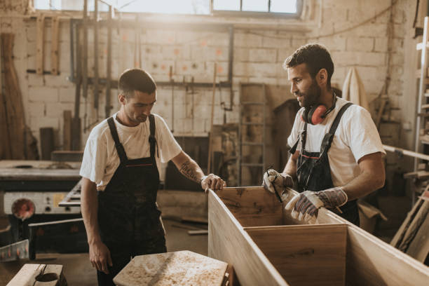 istock Two male workers communicating while making furniture in carpentry workshop. 1145021614