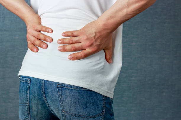 istock A man puts his hand on a sore back, close-up rear view 1145021726