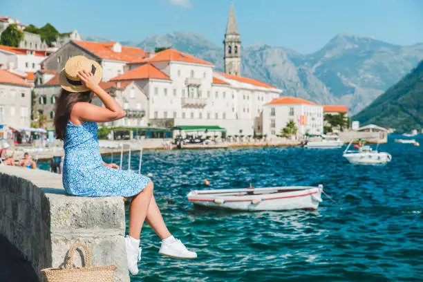 woman walking by Perast city. summer vacation. sea bay. mountains on background