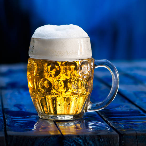 Glass of beer on the blue wooden background.