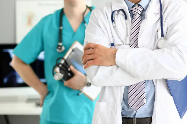 Photo of Male doctor with arms crossed on chest standing in line with colleagues in office