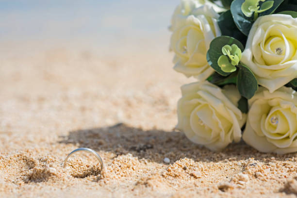 Abstract tropcial beach wedding concept with handprint and ring in sand with bouquet