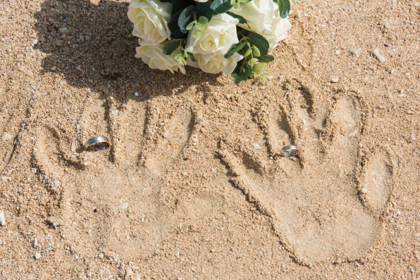 istock Handprints in sand with wedding rings abstract concept 1145027114