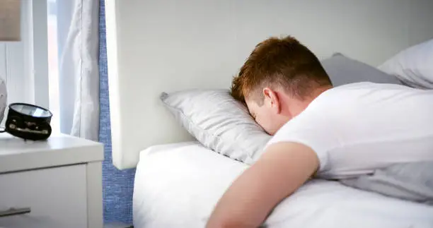 Cropped shot of an unrecognizable young man sleeping face down in frustration in his bedroom