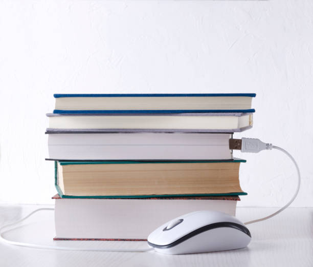 istock Books and computer mouse against white wall.Concept of e-learning 1145030823