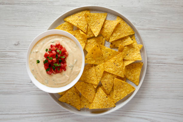 Homemade cheesy dip in a bowl, yellow tortilla chips, top view. Overhead, from above, flat lay. Homemade cheesy dip in a bowl, yellow tortilla chips, top view. Overhead, from above, flat lay. cheese dip stock pictures, royalty-free photos & images