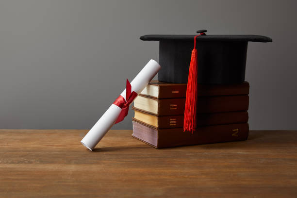 istock Diploma, academic cap and books on wooden surface isolated on grey 1145032028